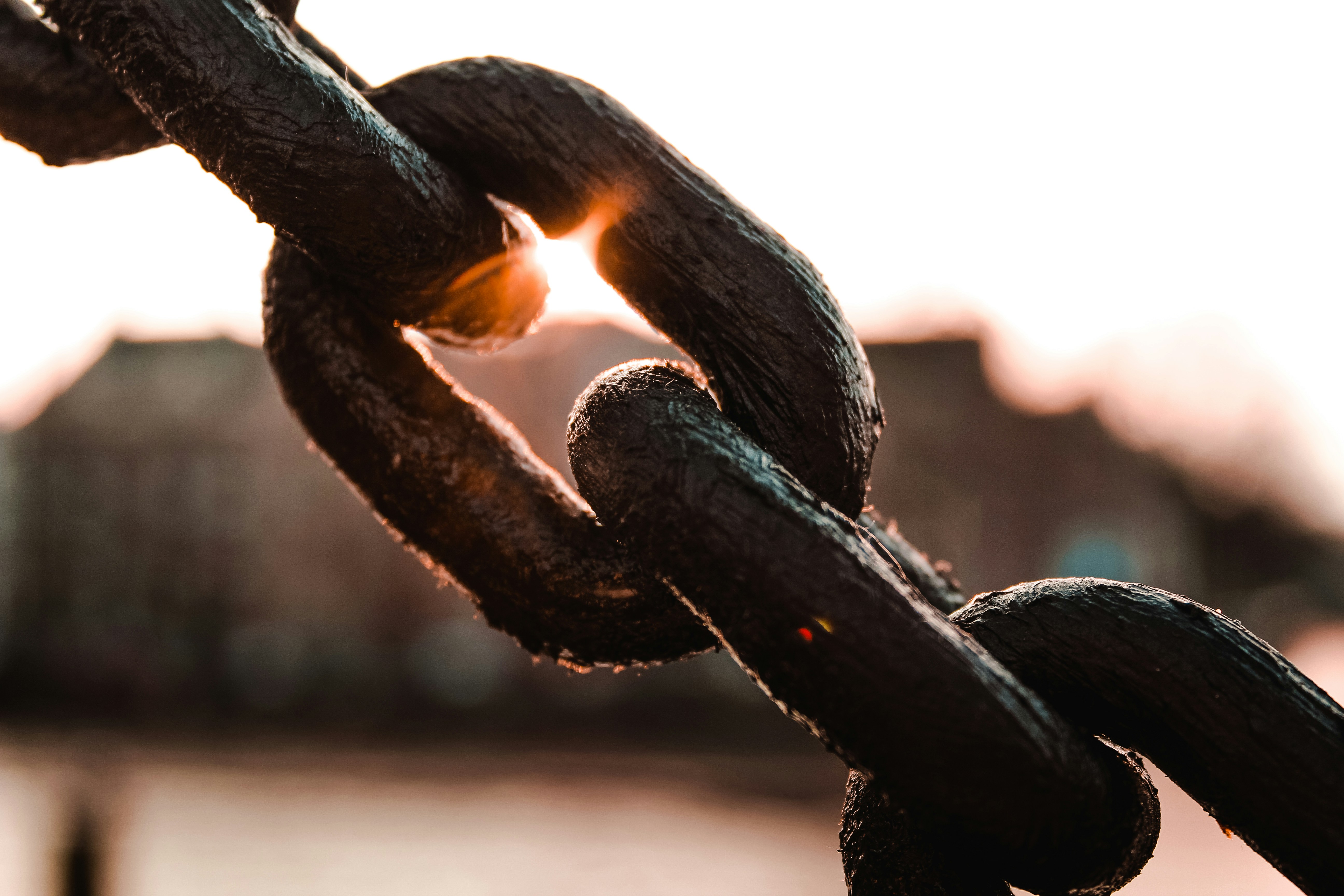 An image depicting a chain with the sun shining behind it.